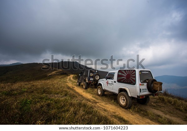 THAILAND - APRIL ,2018 : A\
Suzuki Caribbean drive up on a dirt road  to a steep rocky mountain\
slope.