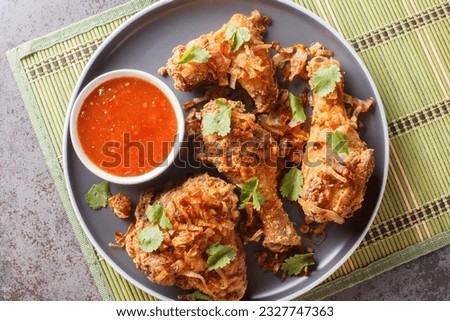 Thailand Hat Yai fried chicken with sweet chili sauce and crispy onions close-up on a plate on the table. Horizontal top view from above
