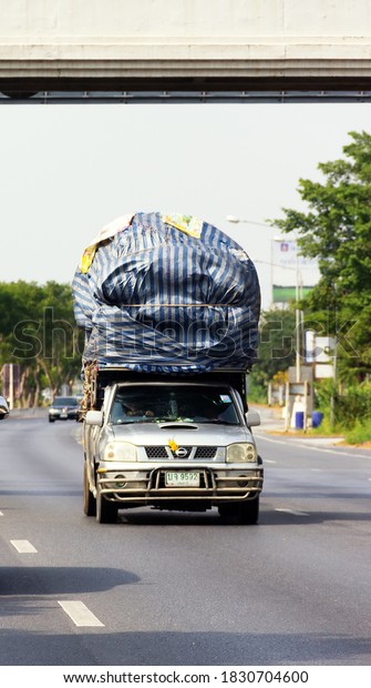 Thailand, Nakhon Sawan - January 25, 2020: Pickups\
with a large overload, load is larger than car on highway. Farm\
small business cars at\
work
