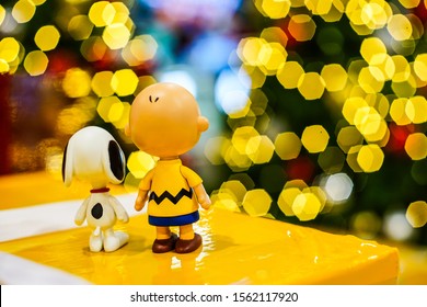 Thailand - November 16, 2019 :  Snoopy And Charlie Brown Plastic Toys Standing Looking At A Light Bokeh Christmas Background.