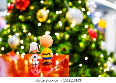 Thailand - November 16, 2019 :  Snoopy And Charlie Brown Plastic Toys Standing Looking At A Light Bokeh Christmas Background.