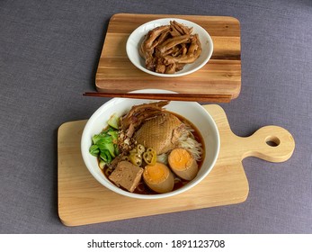 Thai-styled Braised Duck Noodle Soup With Eggs, Tofu And Braised Duck Feet In White Bowls On Wooden Serving Tray