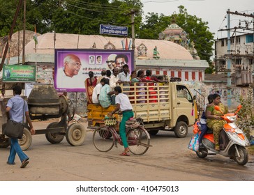 Thanjavur, India - October 15, 2013: A Construction Crew, Males And Females, Is Transported Standing In The Loading Area Of Pickup Truck To Their Job. Concrete Mill Trails The Truck. Street Scene.