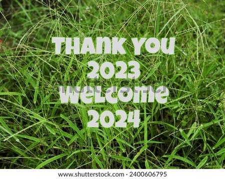 Thank You 2023, Welcome 2024 with green grass background, selective focus.