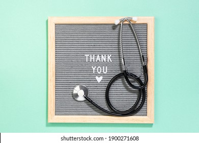 Thank You Card For Doctors And Nurses Concept. World Health Day Greeting Card. Text Thank You On The Letterboard With Medical Stethoscope On Light Turquoise Background.