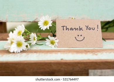 Thank you note with smile face and flower cluster on wooden chair