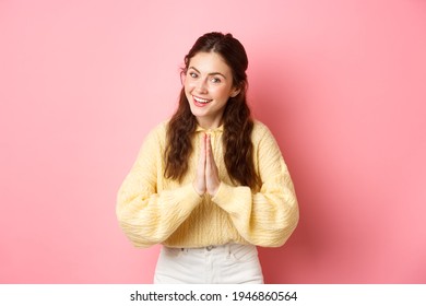 Thank You. Smiling Polite Girl Greeting You With Namaste Gesture, Bowing And Looking Friendly, Express Gratitude, Being Thankful, Standing Over Pink Background