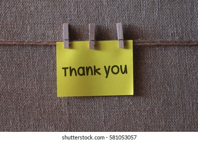 Thank you text on a yellow sticky note with three clips