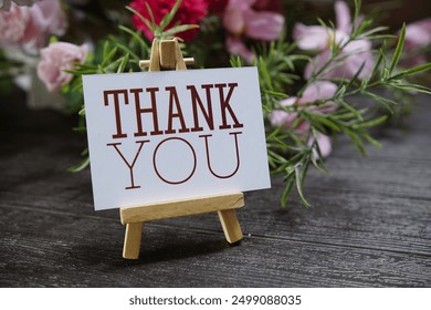 Thank you text write on paper card with wooden easel and flowers decoration on wooden background - Powered by Shutterstock