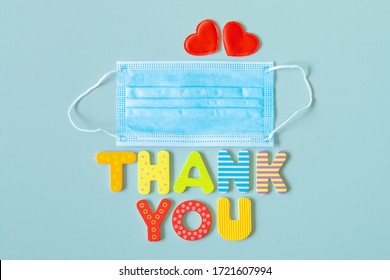 Thank you words with face protective mask. Disposable medical face mask, two hearts and wooden letters text THANK YOU. Appreciation to doctors and nurses. Thanks to medical staff fighting coronavirus