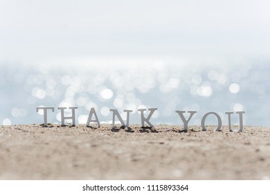 thank you words written on the sand of the beach