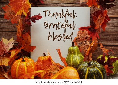 Thankful, Grateful, Blessed Text Message With Autumn Maple Leaves And Pumpkins On Wooden Background