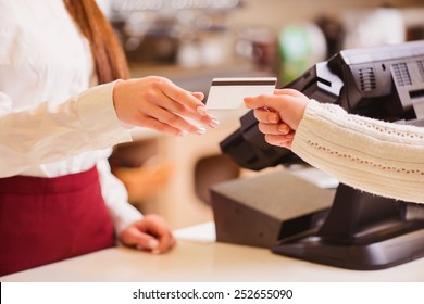 Thanks for your purchase. Cropped image of a customer paying to shop assistant by a credit card at the cash desk - Powered by Shutterstock