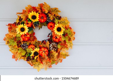 Thanksgiving Autumn wreath with sunflowers, pumpkins and maple leaves on wooden door