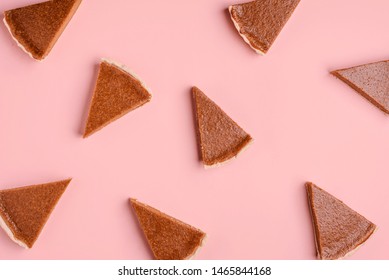 Thanksgiving bakery goods background with pumpkin pie slices random on a pink paper background. Flat lay of pie pieces pattern. Autumn cake pattern.