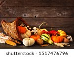 Thanksgiving cornucopia filled with autumn pumpkins and vegetables against a rustic dark wood background
