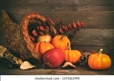 Thanksgiving cornucopia filled with pumpkins and apples against a rustic wooden background - Shutterstock ID 1191061990