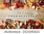 Thanksgiving day autumn background with Happy Thanksgiving letters, seasonal autumn nature berries, pumpkins, apples and flowers on the wooden background, Thanksgiving day card