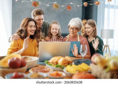 Thanksgiving Day, Autumn Feast. Happy Family Sitting At The Table, Celebrating Holiday And Having Remote Conversation Using Laptop. Grandmother, Mother, Father And Children. Traditional Dinner.