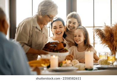 Thanksgiving Day, Autumn feast. Happy family sitting at the table and celebrating holiday. Grandparents, mother and children. Traditional dinner. - Powered by Shutterstock