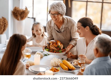 Thanksgiving Day, Autumn feast. Happy family sitting at the table and celebrating holiday. Grandparents, mother and children. Traditional dinner. - Powered by Shutterstock