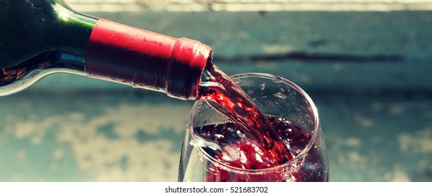 Thanksgiving Day. Christmas. Celebration. Pouring Red Wine. Wine In A Glass. Selective Focus, Motion Blur, Red Wine In A Glass. Sommelier Wine Into The Glass On A Blue Background Old.