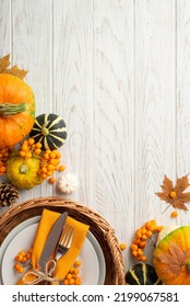 Thanksgiving Day Concept. Top View Vertical Photo Of Rattan Basket With Plate Knife Fork Napkin Pumpkins Pattypan Pine Cone Maple Leaves Rowan On Isolated White Wooden Table Background With Copyspace