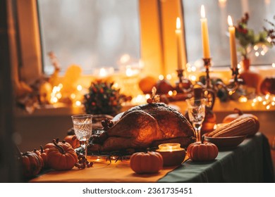 Thanksgiving day dinner with holiday autumn decor and candles. Family dining room table set with delicious golden roasted turkey on platter garnished rosemary fresh small pumpkins - Powered by Shutterstock