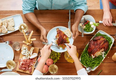 Thanksgiving Day, Eating And Leisure Concept - Group Of People Having Roast Chicken Or Turkey For Dinner At Table With Food