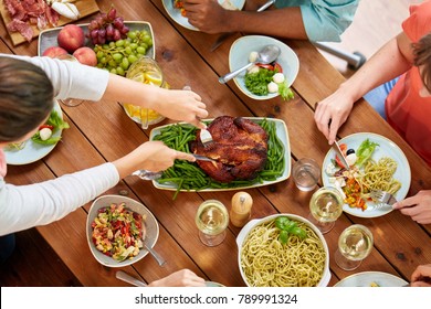 Thanksgiving Day, Eating And Leisure Concept - Group Of People Having Roast Chicken Or Turkey For Dinner At Table With Food