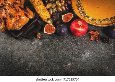 Thanksgiving Day Food. Roasted Whole Chicken Or Turkey With Autumn Vegetables And Fruits: Corn, Pumpkin, Pumpkin Pie, Figs, Apples, On Dark Grey Background, Top View  Copy Space