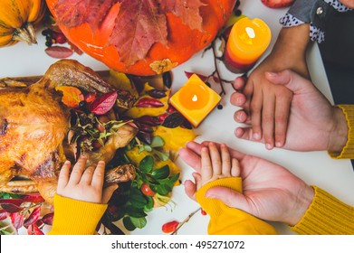 Thanksgiving day. Hands of woman, two child - caucasian boy and multi ethnic or multi race girl. Boy trying give peace of turkey. Flat view. Pumpkins, hands, candles, turkey on view. 