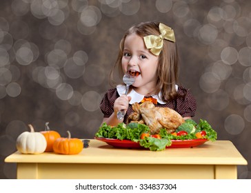 Thanksgiving Dinner.  Adorable Little Girl Sitting At A Small Table With A Small Turkey (chicken) On A Bed Of Greens And Other Vegetables.  Room For Your Text.