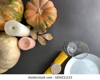 Thanksgiving Dinner Autumn Background. Top View With Plate, Wine Glass, Napkin, Pumpkins And Candles On Dark Surface Table