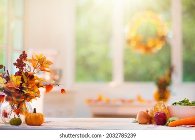 Thanksgiving dinner preparation. Table with pumpkin, carrot and onion for autumn season pie. Decorated kitchen in Halloween season. Cooking celebration feast. Fall seasonal vegetables.