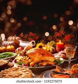 Thanksgiving dinner. Roasted turkey garnished with cranberries on a rustic style table decoraded with pumpkins, vegetables, pie, flowers and candles
