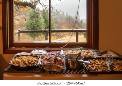 Thanksgiving Dinner Served In Pans On Table By Window Looking Outside Of Cabin In The Woods On Rainy Day