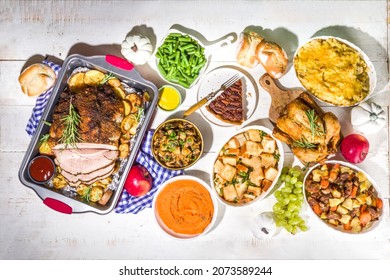 Thanksgiving dinner table with new traditional thanksgiving food - chicken, mashed sweet potatoes, green beans, pecan pie, baked ham pork, mac and cheese, stuffing, modern hard sunny light flatlay - Powered by Shutterstock