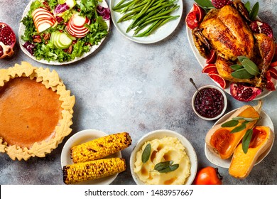 Thanksgiving dinner table with roasted whole chicken or turkey, green beans, mashed potatoes, cranberry sauce and grilled autumn vegetables. Top view, frame. 