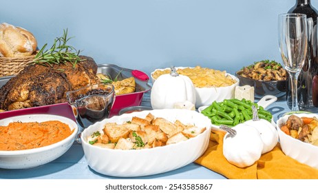 Thanksgiving feast; roasted chicken on herbs in red pan, sweet potatoes, croutons, green beans, gratin, mushrooms, bread rolls, white pumpkins, light blue tablecloth, festive meal vibe. - Powered by Shutterstock