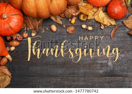 Thanksgiving Greetings. Pumpkins and dry leaves on a dark wooden background. Top view. Flat layer