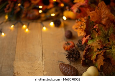Thanksgiving or Halloween, Autumn composition with dry leaves and small pumpkins on an old wooden table with glowing lights. View from above. Copy space autumn mood