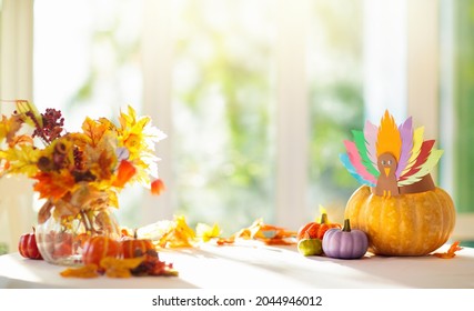 Thanksgiving Home Decoration. Turkey Arts And Crafts Hat On Pumpkin. Traditional Autumn Décor At Big Sunny Window. Table Setting For Family Dinner. Festive Decorated Dining Table.