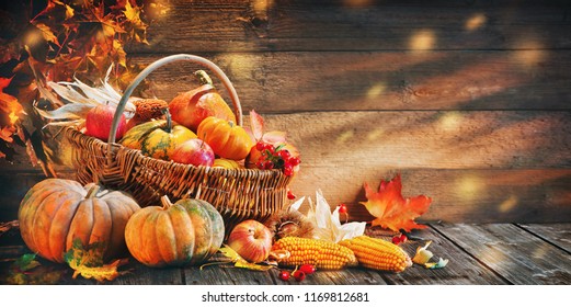 Thanksgiving pumpkins with fruits and falling leaves on rustic wooden table - Powered by Shutterstock