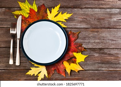 Thanksgiving Table With An Empty Blue Plate And Orange Leaves Decoration On A Wooden Background. Autumn Food Background. Above View Of An Empty Dish. Copy Space, Flat Lay.