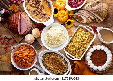 Thanksgiving table with roasted turkey, sliced ham and side dishes