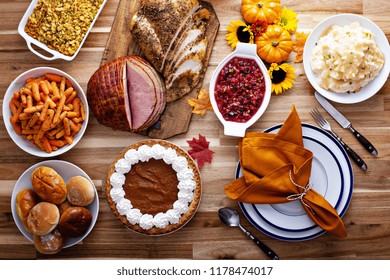 Thanksgiving Table With Roasted Turkey, Sliced Ham And Side Dishes