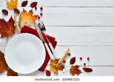 Thanksgiving Table Setting Table. Empty Plate With Cutlery And Napkin, Autumn Leaves On A White Wooden Table. Thanksgiving Holidays Background Concept