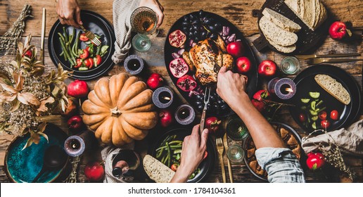 Thanksgiving table setting. Flat-lay of couple eating and drinking champagne at table with roasted chicken, vegetables, fig pie, fruit, candles over wooden table background, top view, wide composition - Shutterstock ID 1784104361
