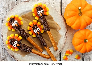 Thanksgiving turkey pretzel rods with candy corn, above over a white wood background